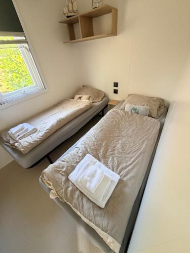 two beds in a small room with a window at Strand chalet Makkum in Makkum