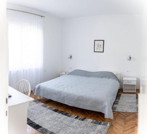 a white bedroom with a bed and a rug at Apartmani Ljubica in Selce