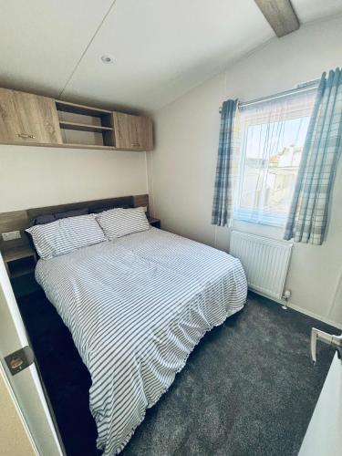 a bedroom with a bed with a striped comforter at SEA VIEW CARAVAN Disability friendly in Caister-on-Sea