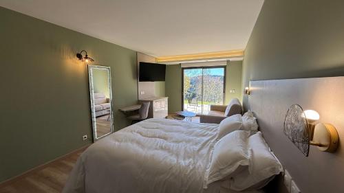 a bedroom with a white bed and a mirror at La Rose du Lac Hôtel Appart' in Coucouron
