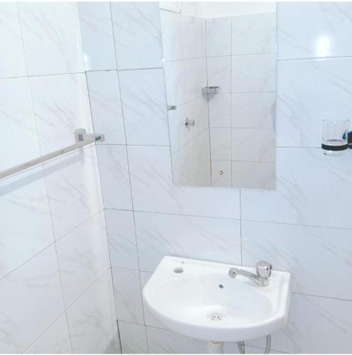a white bathroom with a sink and a mirror at kandys place in Watamu