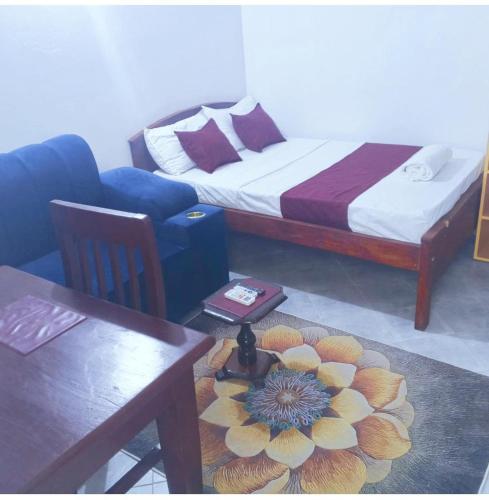 a room with a bed and a table with a flower on the floor at kandys place in Watamu