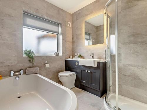a bathroom with a tub and a toilet and a sink at 3 Bed in Maryport oc-82438 in Dearham