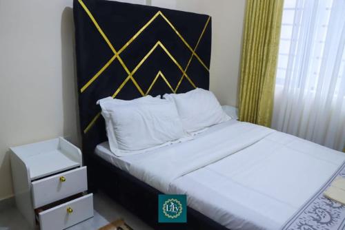 a bedroom with a bed with a black and gold headboard at Executive 1BR with Free WiFi & Netflix in Nyeri