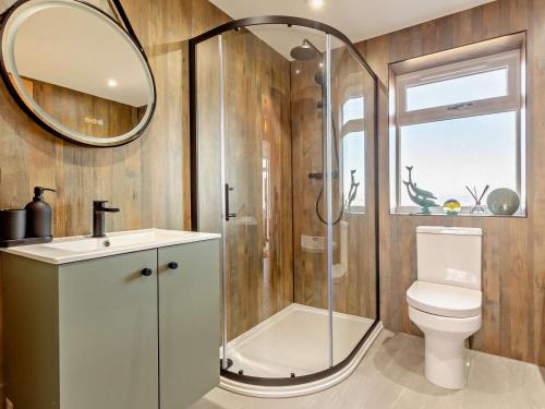 a bathroom with a shower and a toilet and a mirror at 4 Bed in Wick oc-95612 in Huna