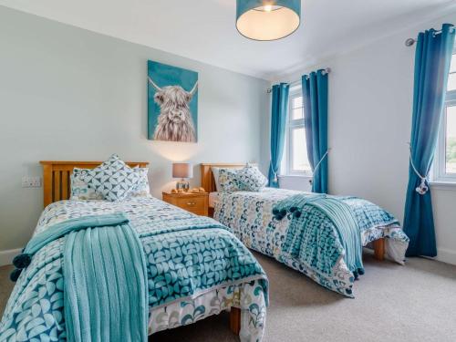 two beds in a room with blue curtains at 2 Bed in Fort William oc-83310 in Onich