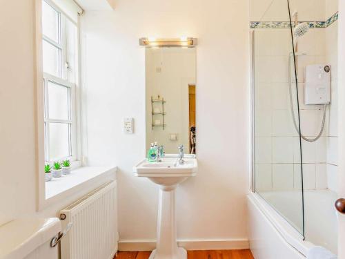 a white bathroom with a sink and a shower at 2 Bed in Dingwall oc-ca387 in Cononbridge