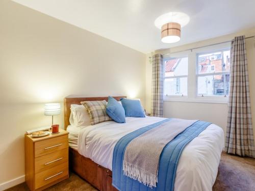 a bedroom with a bed with blue pillows and a window at 2 Bed in Anstruther oc-80648 in Pittenweem
