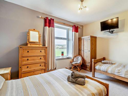 a bedroom with a bed and a television and a window at 2 Bed in Millom oc-93608 in Millom
