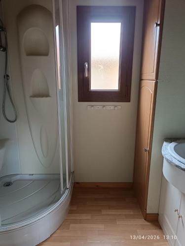 a bathroom with a shower and a sink and a window at La Taillade de Montségur location de Chalets en bois in Fougax-et-Barrineuf