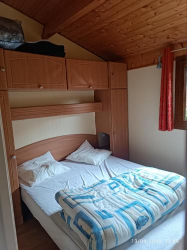 a bed in a room with a wooden ceiling at La Taillade de Montségur location de Chalets en bois in Fougax-et-Barrineuf