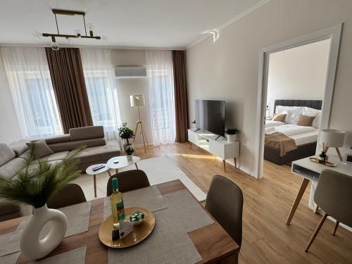 a living room with a table and a living room with a bed at Európa Apartman Mini in Békéscsaba