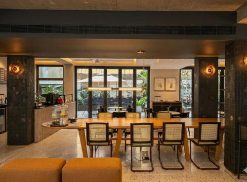 a dining room with a large wooden table and chairs at Wellesley Hotel in Pune
