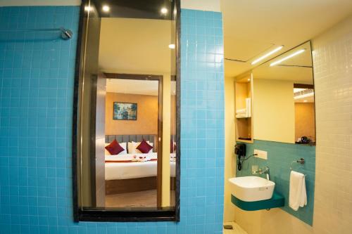 a bathroom with a mirror and a bed and a sink at Ascot Hotel in Kozhikode