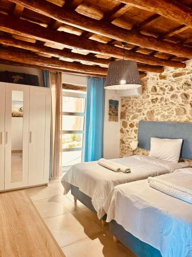 a bedroom with two beds and a stone wall at Harmony Family house in Kerames