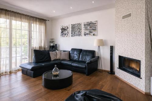 a living room with a black leather couch and a fireplace at Apartment Vila Pavlovski in Bled