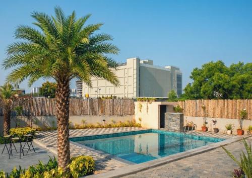a swimming pool with a palm tree and a fence at VILLA De OMR, Private Pool Villa at Old Mahabalipuram Road, Chennai in Kelambākkam
