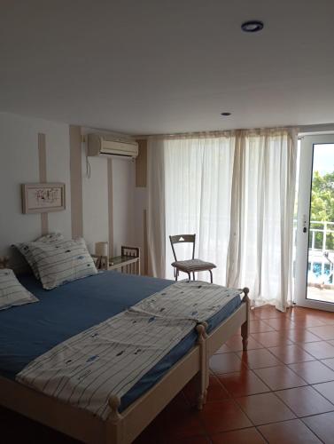 a bedroom with a bed and a chair and a window at Villa Magnet in Lozenets