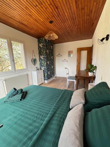 a bedroom with a green bed with a wooden ceiling at Maison chaleureuse de village - location à la chambres in Lanans