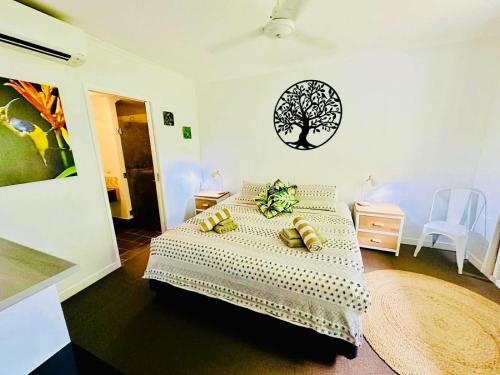 a bedroom with a bed with a tree on the wall at Sunbird Suite in Palm Cove in Palm Cove