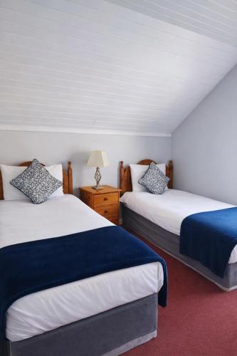 a bedroom with two beds and a table with a lamp at Aran View Holiday Homes Doolin - The Courtyard House - Sleeps 9 in Knockfin Cross Roads