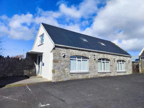 a stone house with a black roof at Aran View Holiday Homes Doolin - The Courtyard House - Sleeps 9 in Knockfin Cross Roads
