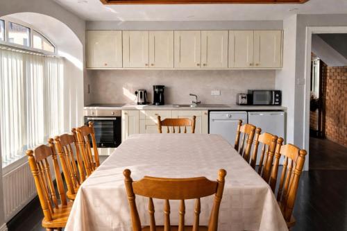 a kitchen with a table and chairs and a kitchen with white cabinets at Aran View Holiday Homes Doolin - The Courtyard House - Sleeps 9 in Knockfin Cross Roads