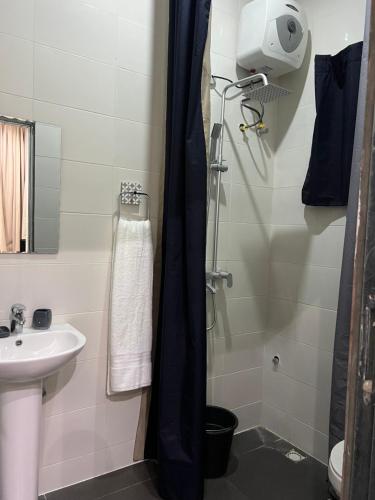 a small bathroom with a sink and a shower at The Mishkan Apartments in Kaduna