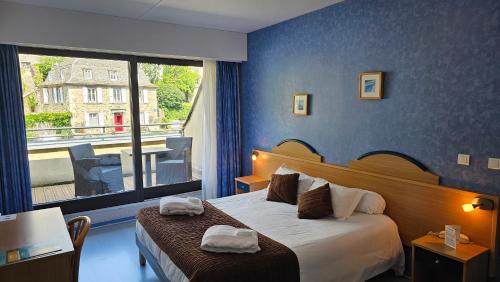 a hotel room with a bed and a large window at Brit Hotel Du Ban in Chaudes-Aigues