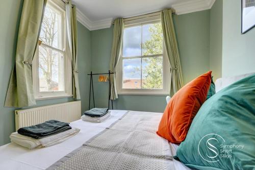 a bedroom with a large bed with two windows at Warwick Place Apartments in Leamington Spa