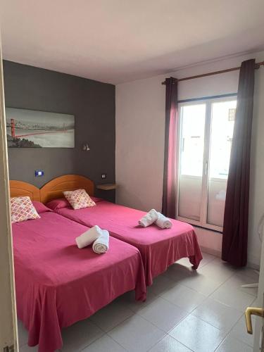 a bedroom with two beds with pink sheets and a window at Aguazul 120 in Tías