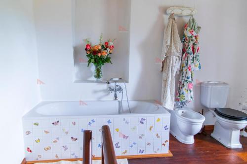 a bathroom with a tub and a toilet and a vase of flowers at Casa Torre Adults Only storia e relax a Fiorenzuola in Fiorenzuola di Focara
