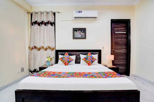 a bedroom with a large white bed with colorful pillows at Sarla Residency in Noida