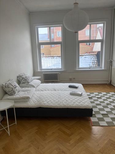 a bed in a room with two windows at Charmigt boende på i centrala Helsingborg in Helsingborg