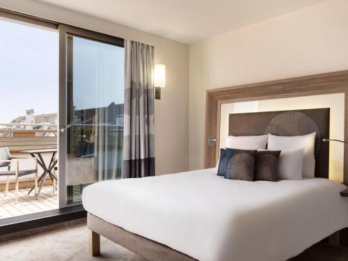 a bedroom with a large bed and a large window at Novotel Genève Centre in Geneva