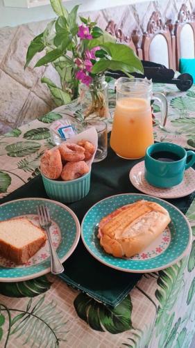 a table topped with plates of food and orange juice at Pousada Renascer in Mangaratiba