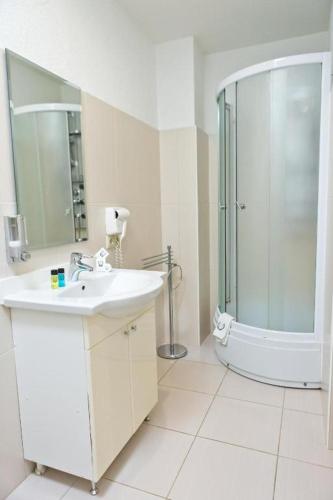 a white bathroom with a sink and a shower at Hotel Olsi in Chişinău
