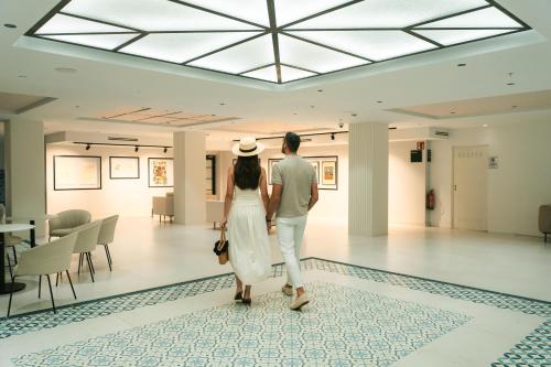 a man and a woman looking at art in a museum at Hotel Villa España in Benidorm
