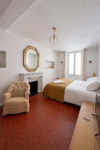 a bedroom with a bed and a chair and a mirror at Maison BOBLEU in Bandol
