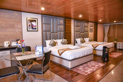 a bedroom with two beds and a desk and a table at Anutri Hotels & Resorts in Jāmb
