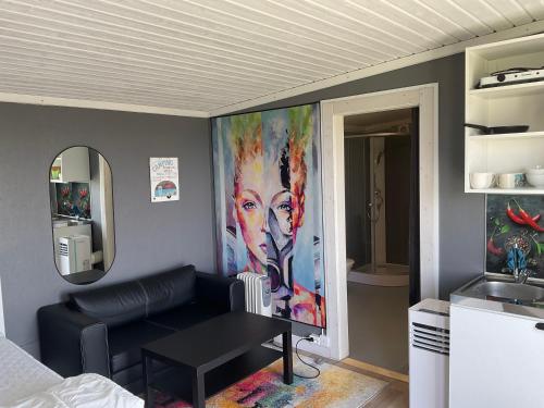 a living room with a couch and a painting on the wall at Klinta Seaview Cabin ensuite in Köpingsvik