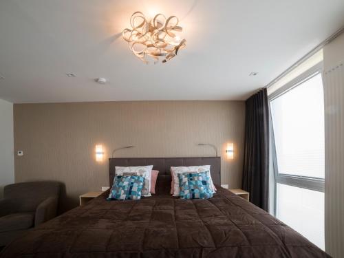 a bedroom with a bed with a couch and a chandelier at Q Studio in Herzele