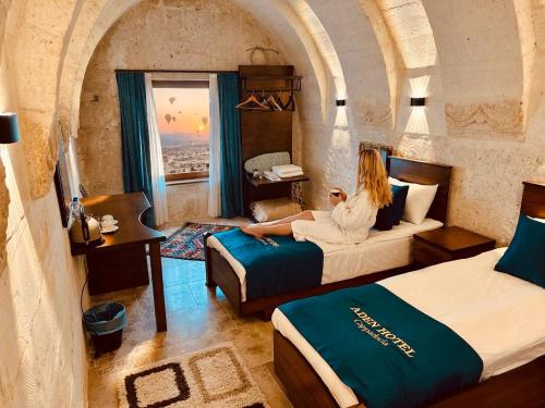a woman sitting on a bed in a hotel room at Aden Hotel Cappadocia in Uçhisar