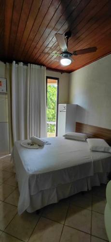 a bedroom with a bed with a ceiling fan at Pousada Costa do Sol in Aracruz
