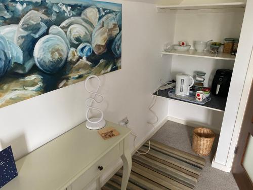 a room with a table and a painting on the wall at The Threshing Barn Loft in Pont-y-Berem
