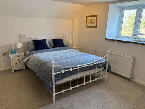 a bedroom with a bed with blue sheets and a window at The Threshing Barn Loft in Pont-y-Berem