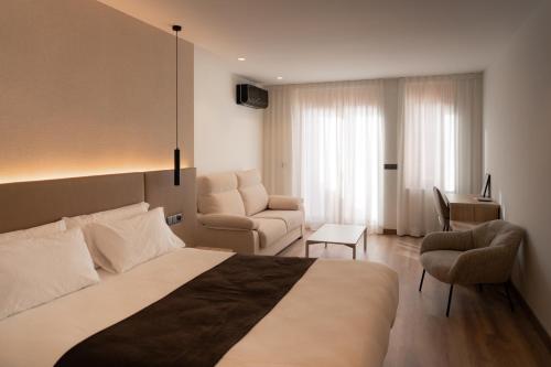 a bedroom with a bed and a couch and a chair at L'Agora Rooms in Bocairent