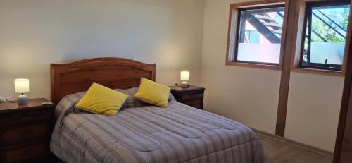 a bedroom with a bed with two yellow pillows at El gran Jacarandá in Viña del Mar