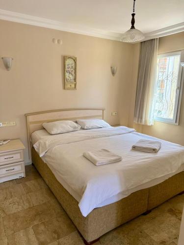 a bedroom with a large bed with two towels on it at Dove Apart Hotel in Fethiye