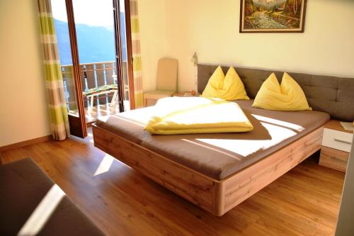 a bed with yellow pillows on it in a room at Eichmannhof in Marlengo